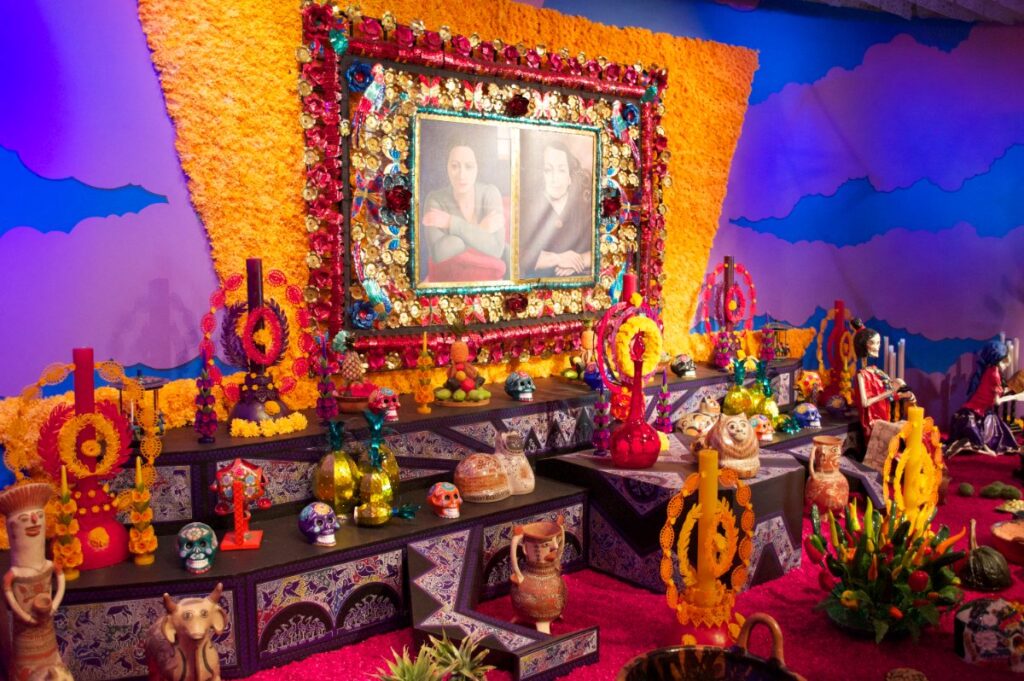 Gran ofrenda de Día de Muertos con cempasúchil, velas, calaveras y retratos
