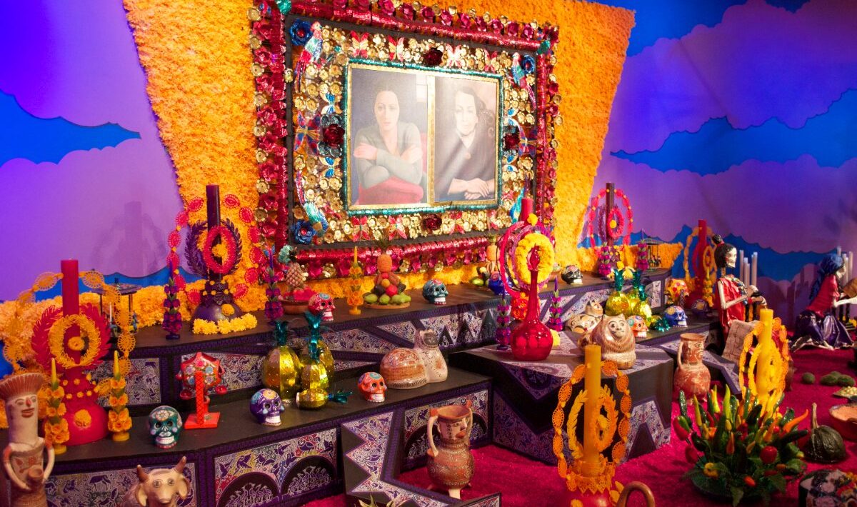 Gran ofrenda de Día de Muertos con cempasúchil, velas, calaveras y retratos