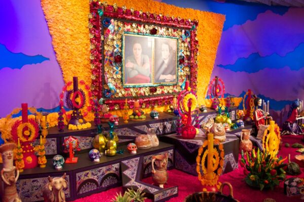 Gran ofrenda de Día de Muertos con cempasúchil, velas, calaveras y retratos