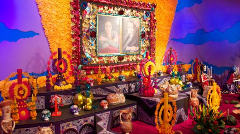 Gran ofrenda de Día de Muertos con cempasúchil, velas, calaveras y retratos