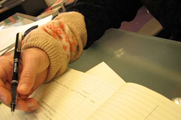 Mano escribiendo apuntes en un cuaderno con bolígrafo