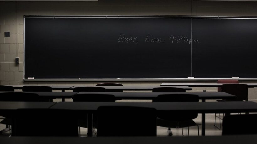 Aula vacía con un examen anunciado en la pizarra