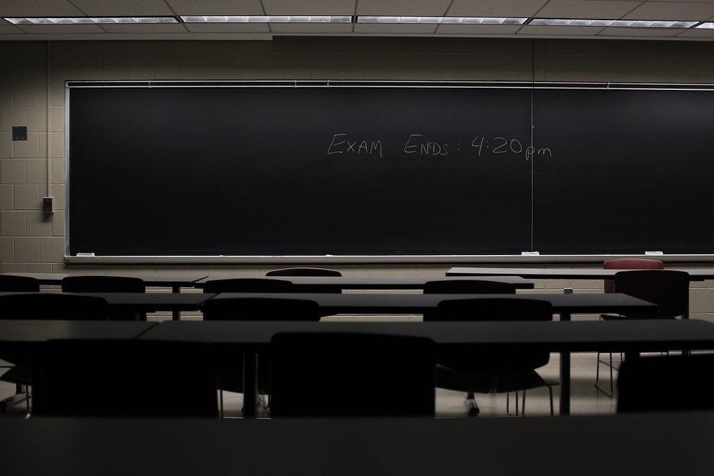 Aula vacía con un examen anunciado en la pizarra