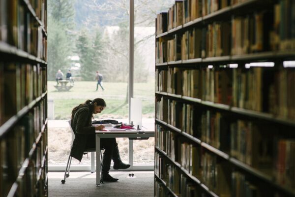Estudiante leyendo en una biblioteca universitaria