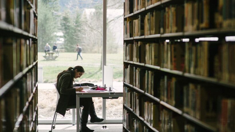 Estudiante leyendo en una biblioteca universitaria
