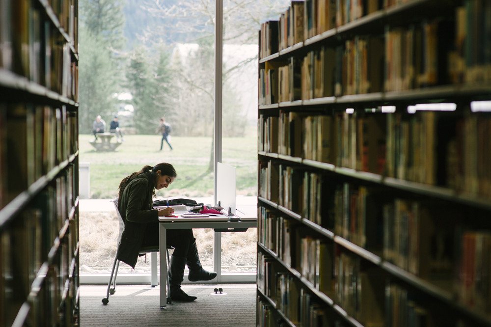 Estudiante leyendo en una biblioteca universitaria
